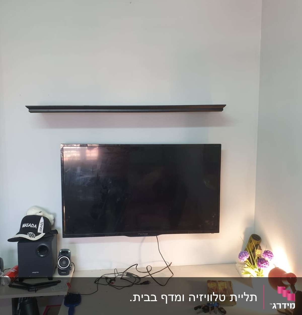 מדף תלוי מעל טלוויזיה עם חוטים על שולחן
